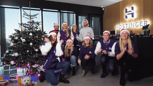 A Group Of People Posing For A Picture In Front Of A Hostinger Logo GIF