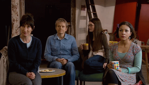 A Group Of People Sitting Around A Table With A Plate Of Food On It GIF