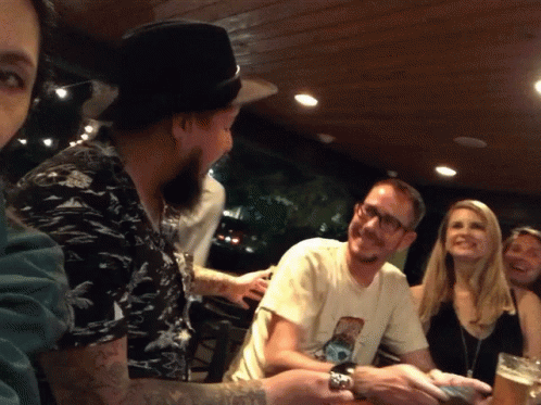 A Group Of People Sitting Around A Table With One Man Wearing A T-Shirt With A Picture Of A Dog GIF