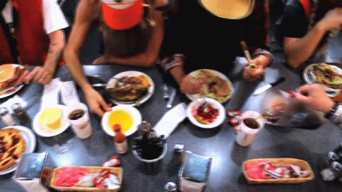 A Group Of People Sitting At A Table Eating Food GIF