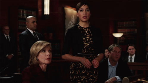 A Group Of People Sitting At A Table In A Courtroom GIF