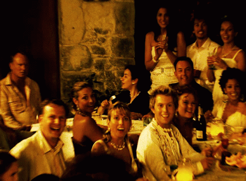 A Group Of People Sitting At A Table With A Bottle Of Wine On The Table GIF
