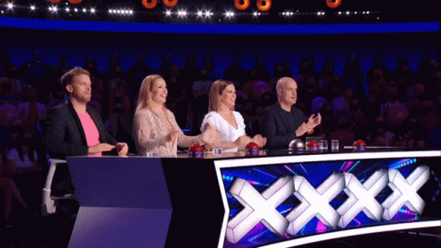 A Group Of People Sitting At A Table With A Sign That Says Xxx On It GIF