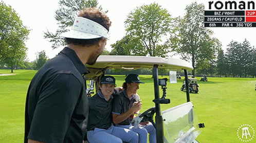 A Group Of People Sitting In A Golf Cart On A Golf Course With Roman Written On The Bottom GIF