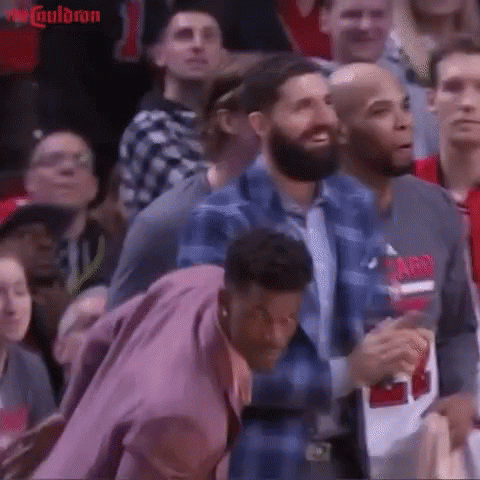 A Group Of People Sitting In A Stadium Watching A Basketball Game GIF