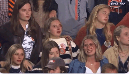 A Group Of People Sitting In A Stadium With One Wearing A Shirt That Says " Tigers " GIF
