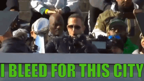 A Group Of People Sitting In A Stadium With The Words I Bleed For This City GIF
