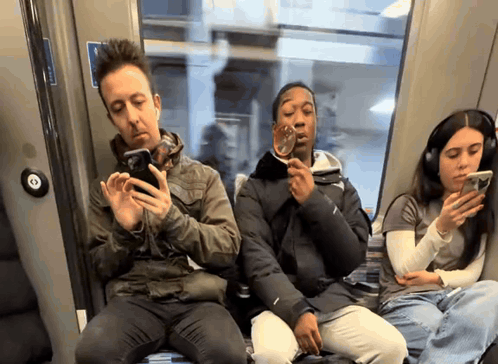 a group of people sitting on a bus looking at their cell phones