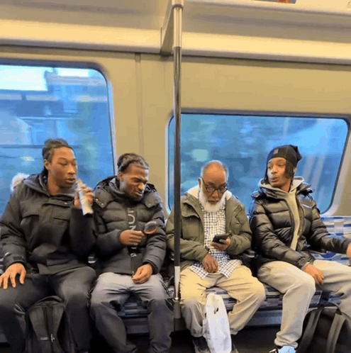 a group of people sitting on a bus with one wearing a jacket that says nautica on it