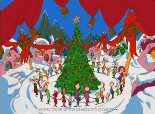 A Group Of People Standing Around A Christmas Tree GIF
