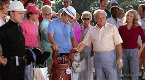 A Group Of People Standing Around A Golf Bag With A Tag That Says Giant Monster On It GIF