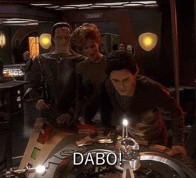 a group of people standing around a roulette table with the word dabo on it
