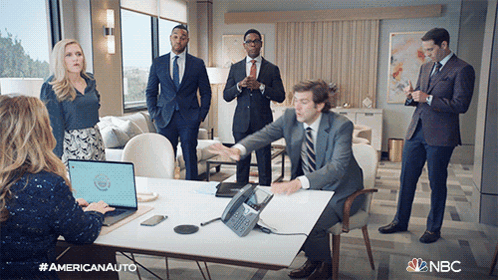 Group Of People Around Table With NBC Logo GIF