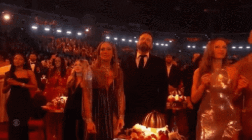 A Group Of People Standing In A Dark Room With A Cbs Logo On The Bottom Right GIF