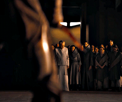 A Group Of People Standing In A Dark Room With A Man Holding A Sword GIF