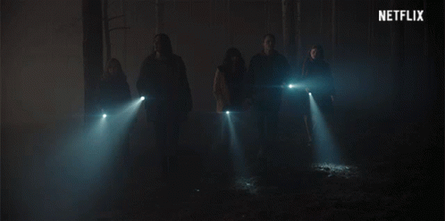 A Group Of People Standing In A Dark Room With A Netflix Logo In The Background GIF