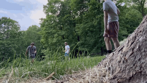 A Group Of People Standing In A Grassy Field GIF