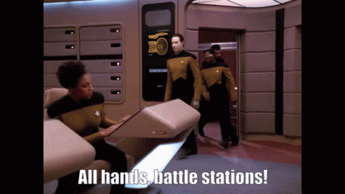 A Group Of People Standing In A Room With The Words " All Hands Battle Stations " On The Bottom GIF