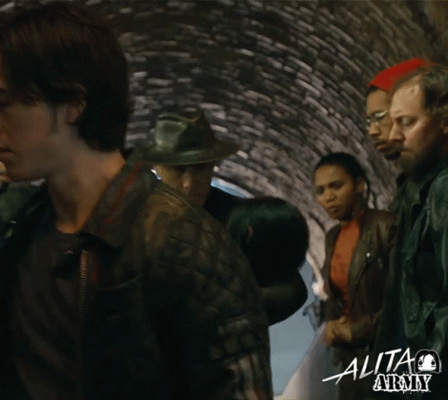a group of people standing in a tunnel with the word alita on the bottom right