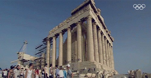 A Group Of People Standing In Front Of A Building With The Olympics Logo In The Background GIF