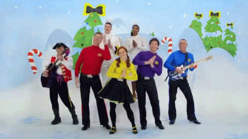 A Group Of People Standing In Front Of A Christmas Tree And Candy Canes GIF