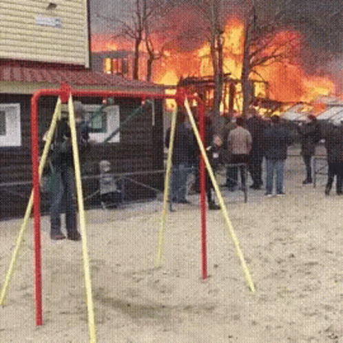 A Group Of People Standing In Front Of A Fire GIF