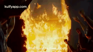 A Group Of People Standing In Front Of A Large Fire . GIF