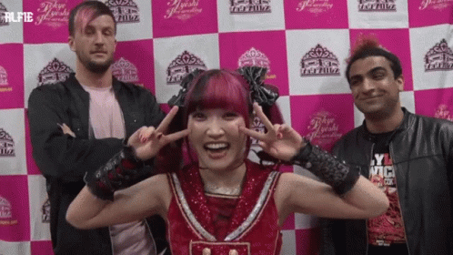 a group of people standing in front of a pink and white checkered wall with the word tokyo on it