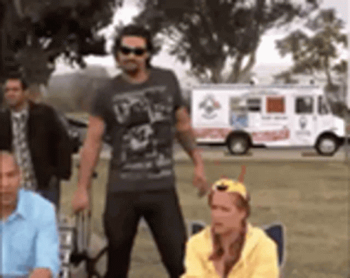 A Group Of People Standing In Front Of A Pizza Truck . GIF