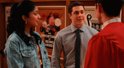 A Group Of People Standing In Front Of A Poster That Says The Important Of Being Earnest GIF