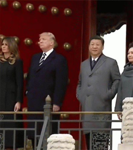A Group Of People Standing In Front Of A Red Wall GIF