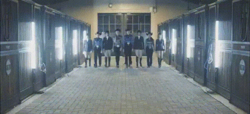 a group of people standing in front of a row of stable doors
