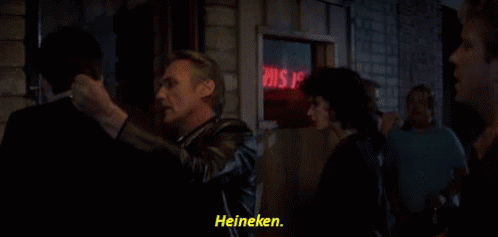 a group of people standing in front of a sign that says heineken