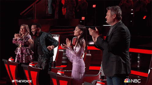 A Group Of People Standing In Front Of A Sign That Says The Voice GIF