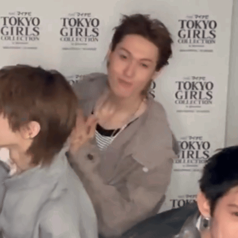 A Group Of People Standing In Front Of A Tokyo Girls Collection Wall GIF