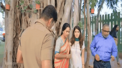 A Group Of People Standing In Front Of A Tree With A Man In A Police Uniform GIF