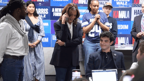 A Group Of People Standing In Front Of A Wall That Says Kamala On It GIF
