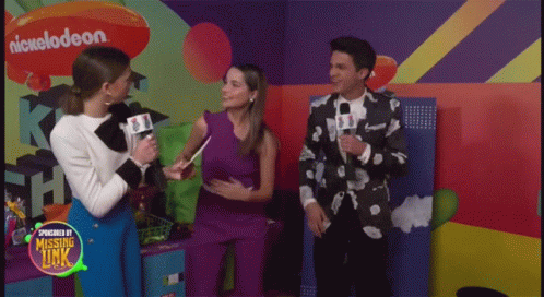 A Group Of People Standing In Front Of A Wall With A Nickelodeon Logo On It GIF