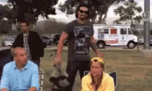 A Group Of People Standing In Front Of An Ice Cream Truck In A Park . GIF