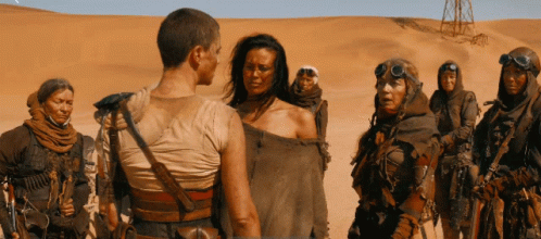 A Group Of People Standing In The Desert With One Wearing A Goggles GIF
