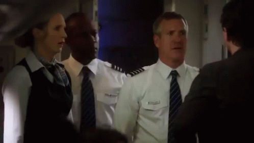 A Group Of People Standing Next To Each Other In A Room . GIF
