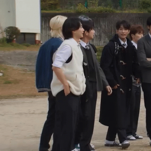 A Group Of People Standing Next To Each Other With One Wearing A Vest GIF