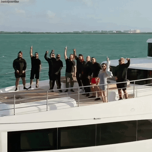 A Group Of People Standing On A Boat With Their Arms Up GIF