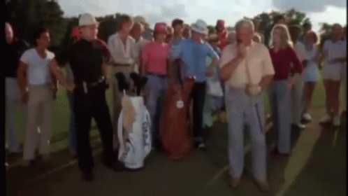 A Group Of People Standing On A Golf Course With A Man Holding A Golf Bag That Says Taylormade On It . GIF