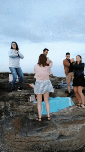 A Group Of People Standing On A Rocky Cliff With A Woman Taking A Picture GIF