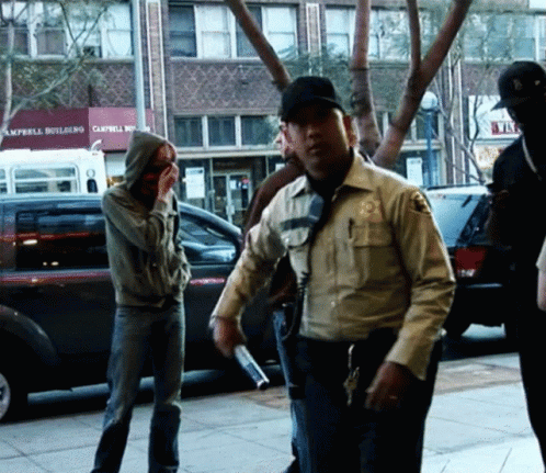 A Group Of People Standing On A Sidewalk In Front Of A Building That Says Campbell Building GIF
