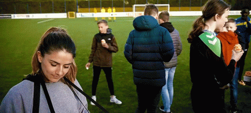 A Group Of People Standing On A Soccer Field Eating Hamburgers GIF