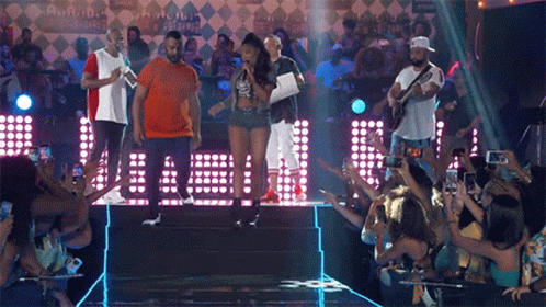 a group of people standing on a stage in front of a crowd taking pictures