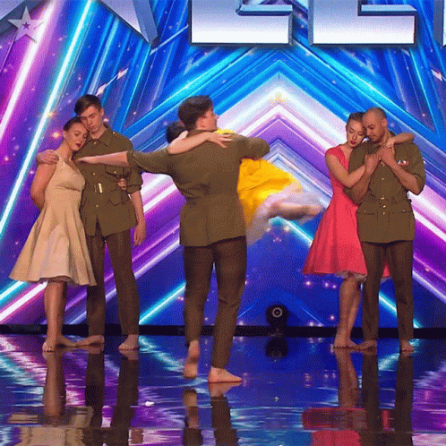 A Group Of People Standing On A Stage In Front Of A Sign That Says ' America ' On It GIF