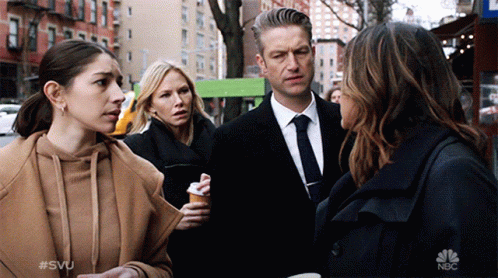a group of people standing on a street with the nbc logo on the bottom left